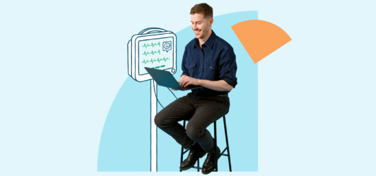 Person sitting on stool holding a laptop with heart monitor attached